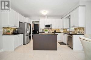 uma cozinha com armários brancos e electrodomésticos de aço inoxidável em Rooms in Luxury Vaughan Home em Vaughan
