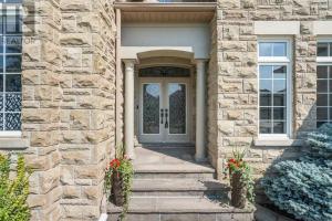 a front door of a stone house with flowers at Rooms in Luxury Vaughan Home in Vaughan