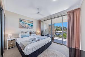 1 dormitorio con cama y ventana grande en Candlelight - Airlie Beach en Airlie Beach