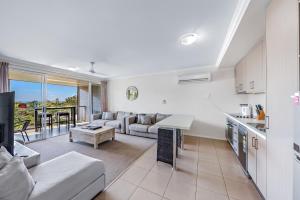 a kitchen and living room with a couch and a table at Candlelight - Airlie Beach in Airlie Beach