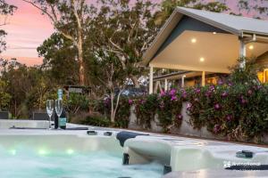 a hot tub with a bottle of wine and wine glasses at Deja Blue in Anna Bay
