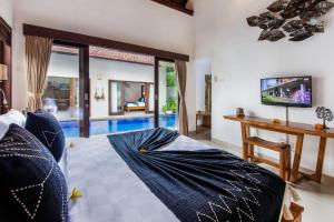 a bedroom with a bed and a tv in it at Villa Joyosa in Seminyak