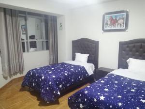 1 dormitorio con 2 camas y sábanas azules con estrellas en Hostal Pacífico Huánuco, en Huánuco