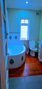 a blue bathroom with a tub and a toilet at Pmb Guest House in Pietermaritzburg