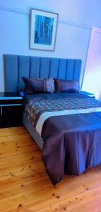 een slaapkamer met een bed met een blauw hoofdeinde bij Pmb Guest House in Pietermaritzburg