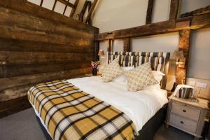 1 dormitorio con 1 cama grande y pared de madera en The White Hart, South Harting, en Petersfield