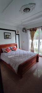 a bedroom with a large wooden bed with red pillows at Secret Garden Homestay in Siem Reap