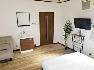 a bedroom with a bed and a sink and a television at Guest House Tatara in Yasugi