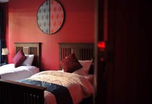 a bedroom with two beds and a red wall at Caiyong in Khlong San