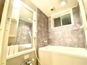 uma casa de banho com uma banheira, um lavatório e um espelho. em 外宮前別邸　星凪庵 em Ise