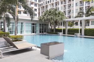 a swimming pool in a building with a chair and palm trees at Jpark Residences at Thammasat Rangsit in Ban Bang Phut (3)