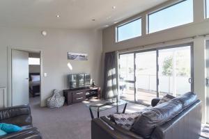 a living room with a leather couch and a television at Stunning Bob Lee Place in Wanaka