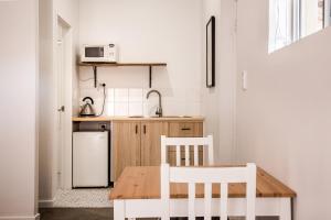 EM Apartments في مارغريت ريفر: مطبخ بطاولة خشبية وكرسيين بيض