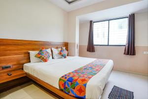 een slaapkamer met een bed met een houten hoofdeinde en een raam bij FabHotel Paradise Inn in Pune