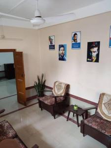a living room with two chairs and posters on the wall at Madrid Homes in Guwahati