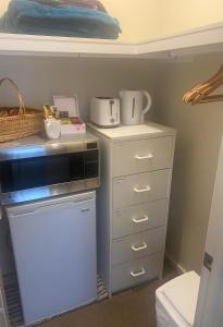 a kitchen with a counter with a microwave and a dresser at Private room with ensuite and parking close to Wollongong CBD in Wollongong