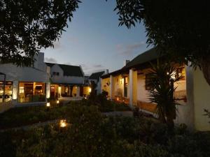 a house with lights in the yard at night at Kaijaiki Country Inn and Restaurant in Yzerfontein