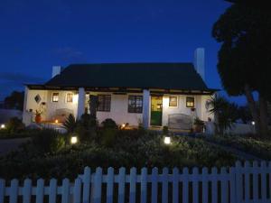 una casa blanca con luces delante de una valla en Kaijaiki Country Inn and Restaurant, en Yzerfontein