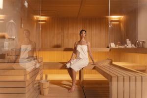 Una donna seduta in una sauna con una sposa di San Michele Relais & Spa a Sirolo