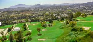 - une vue aérienne sur un parcours de golf avec des montagnes en arrière-plan dans l'établissement Apartamento Marbella, à Marbella