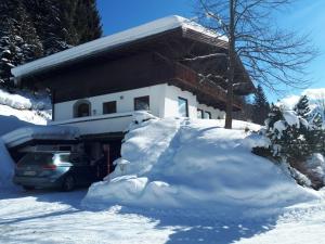 une voiture garée devant une maison recouverte de neige dans l'établissement Ferienwohnung Hans Ebner, à Eben im Pongau