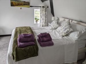 - un lit blanc avec 2 serviettes violettes dans l'établissement Characterful 2 bed cottage, quiet village setting, à Ashleworth