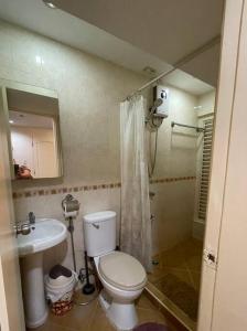 La salle de bains est pourvue de toilettes blanches et d'un lavabo. dans l'établissement Lovely home away from home, à Manille