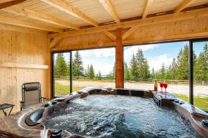 a hot tub in a cabin with a large window at Casa din Deal in Mărişel