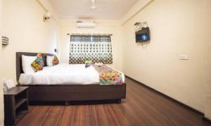 a bedroom with a bed and a television in it at FabHotel East Field Homes in Pune