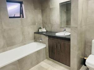 a bathroom with a bath tub and a sink at Manor Hills Guest Lodge in Rustenburg