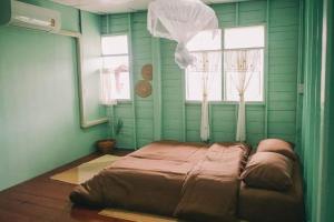 a bed in a room with green walls and windows at Popole in Nonthaburi