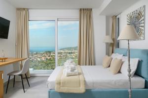 a hotel room with a bed and a large window at Kefi Luxury Villas in Limenas
