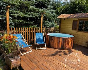 a wooden deck with a hot tub and two chairs at Bieszczady Noclegi "Muzyczna Chata" in Olszanica