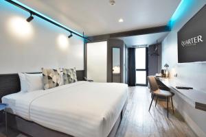 a bedroom with a large white bed and a desk at The Quarter Silom by UHG in Bangkok