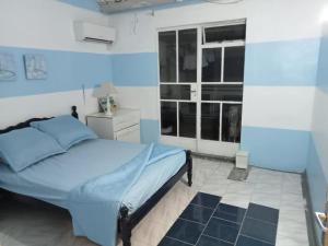 a blue and white bedroom with a bed and a window at La Rêverie Apartment in Trou aux Biches