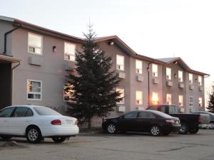dos autos estacionados en un estacionamiento frente a un edificio en South Hill Motor Inn, en Red Deer