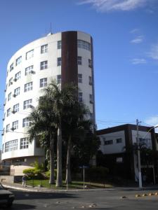 un edificio bianco con palme di fronte di Summit Inn Hotel Pouso Alegre a Pouso Alegre