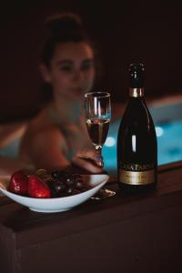 a woman holding a glass of wine next to a plate of fruit at SPA SPA Letná in Prague
