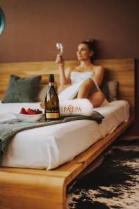 a woman sitting on a bed with a bottle of wine at SPA SPA Letná in Prague