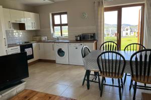 a kitchen with a table and chairs and a kitchen with a washing machine at Achill Sound Holiday Village No 11 in Achill Sound