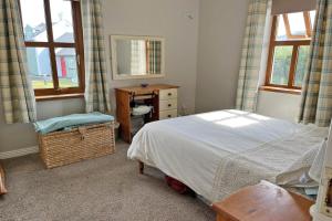 een slaapkamer met een bed, een bureau en ramen bij Achill Sound Holiday Village No 11 in Achill Sound