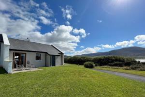 Achill Sound Holiday Village No 11 في Achill Sound: منزل مع ساحة عشبية بجوار مبنى