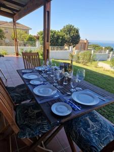 a wooden table with plates and wine glasses on it at HERON COTTAGE - for your seaside holiday. in Chintsa