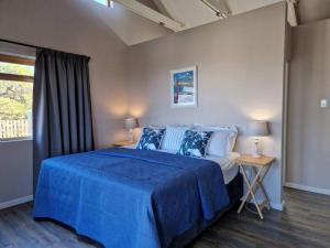 a bedroom with a blue bed and a window at HERON COTTAGE - for your seaside holiday. in Chintsa