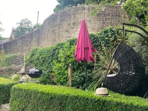 un parapluie rose et un chapeau dans un jardin dans l'établissement The Hideaway, à Ripponden