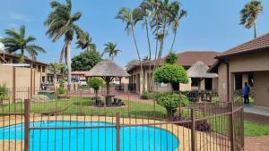 a resort with a swimming pool and palm trees at Gecko Inn in Richards Bay
