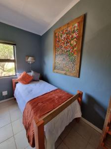 a bedroom with a bed with a painting on the wall at Abaloo Apartment #1 in Sabie