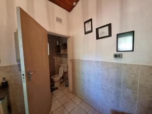 a bathroom with a toilet and some pictures on the wall at Abaloo Apartment #1 in Sabie