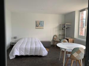 a bedroom with a white bed and a table and chairs at Studio Soligny in Soligny-les-Étangs