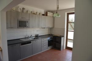 uma cozinha com armários cinzentos, um lavatório e uma janela em Statek Krkavčí Hora em Nižbor